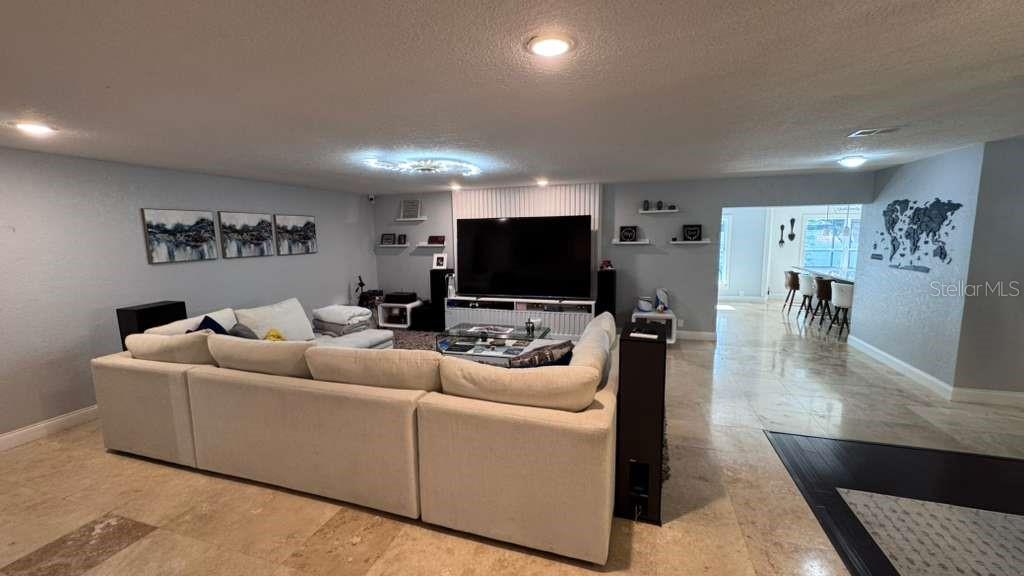 A spacious living room features a large sectional sofa, a wall-mounted television, and tile flooring — 4627 WOODLOT COURT, ORLANDO, FL