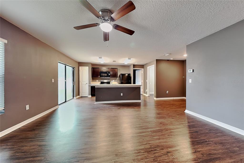 An open-concept kitchen and living area features dark wood flooring and a ceiling fan — 26463 MOTT AVENUE, BROOKSVILLE, FL