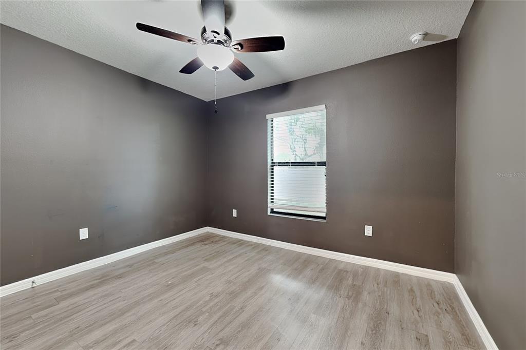 An empty bedroom features dark gray walls, light wood-look flooring, and a ceiling fan — 26463 MOTT AVENUE, BROOKSVILLE, FL