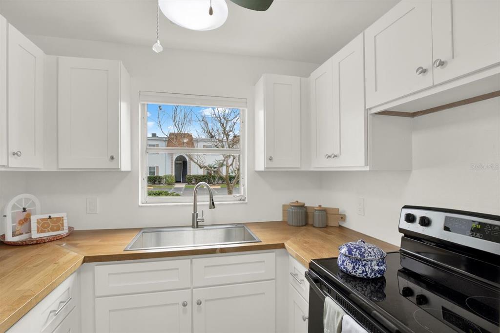 A kitchen features white cabinets, a wood countertop, a stainless steel sink, and a window — 235 S MCMULLEN BOOTH ROAD UNIT 45, CLEARWATER, FL
