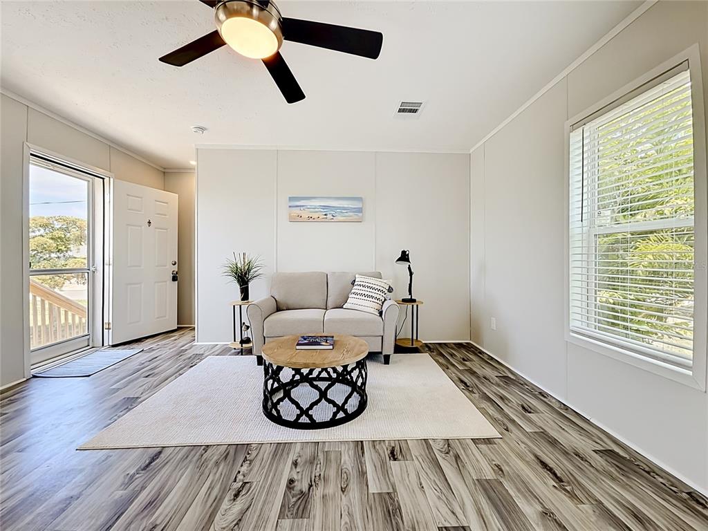 A living room features light wood-look flooring, a beige loveseat, and a round coffee table — 1433 SEAGULL DRIVE, ENGLEWOOD, FL