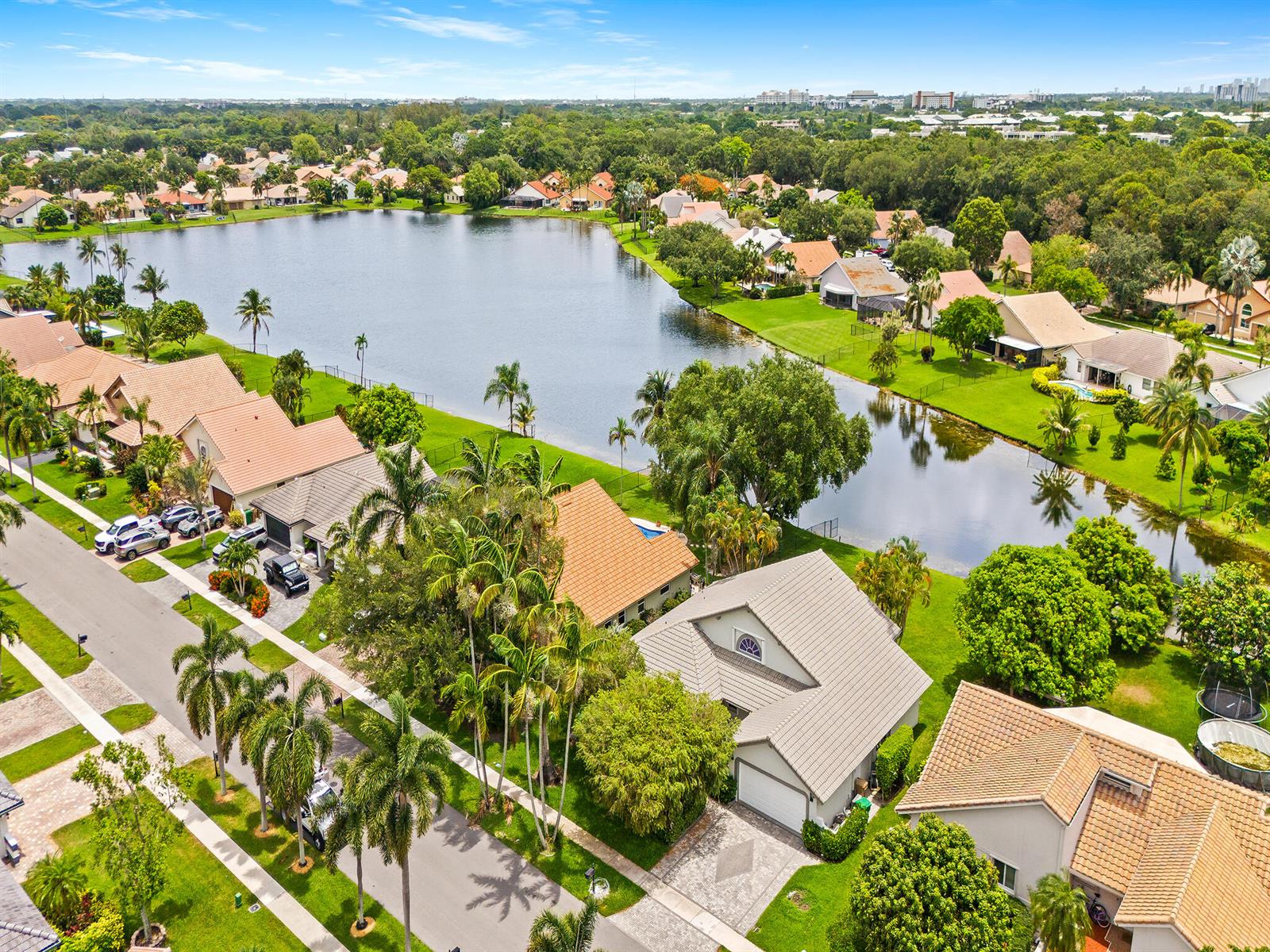 An aerial view shows suburban houses with tiled roofs surrounding a large lake — 1750 W Oak Knoll Circle, Davie FL 33324, DAVIE, FL