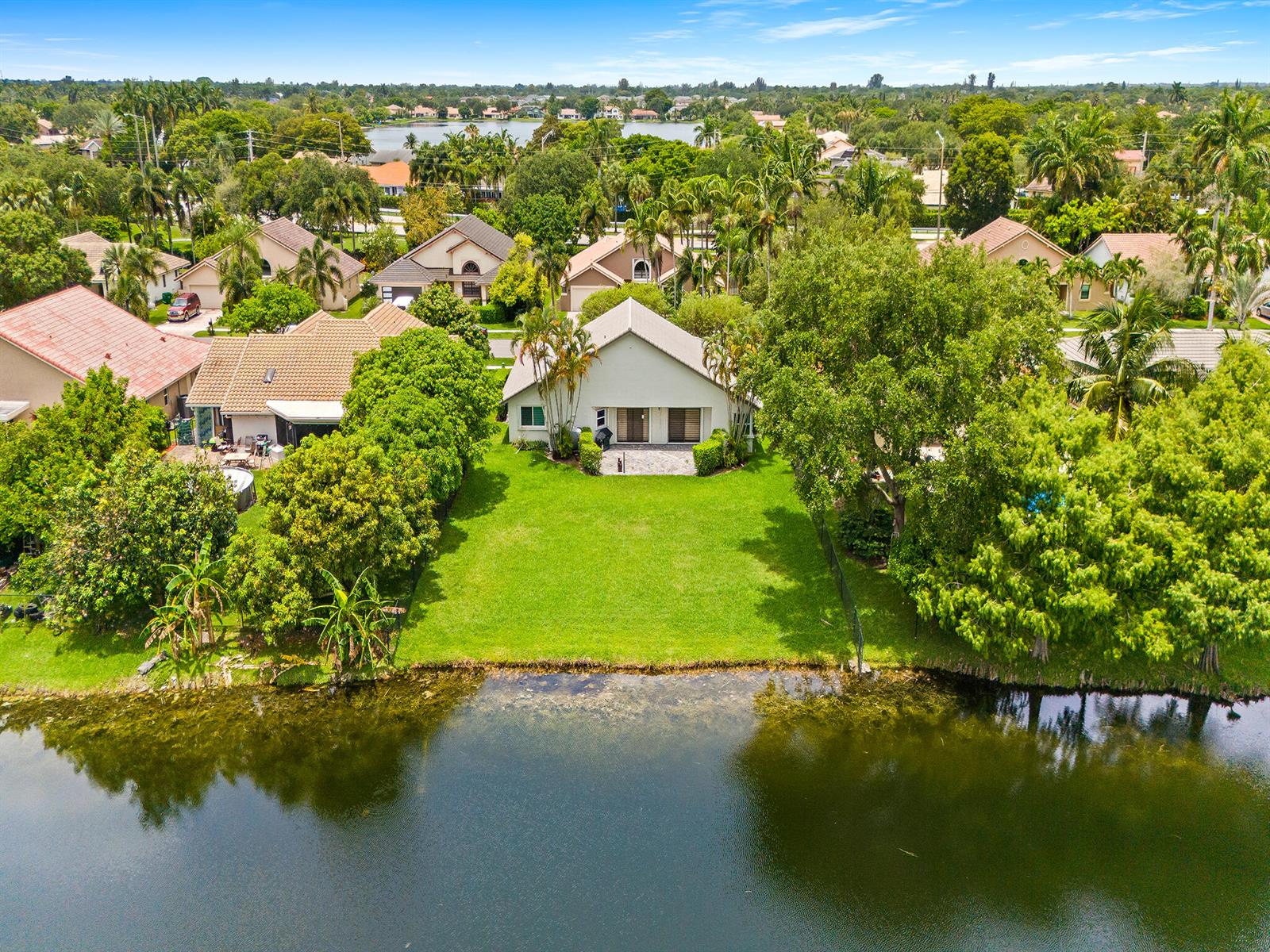 An aerial view shows a single-story house with a large backyard bordering a lake — 1750 W Oak Knoll Circle, Davie FL 33324, DAVIE, FL