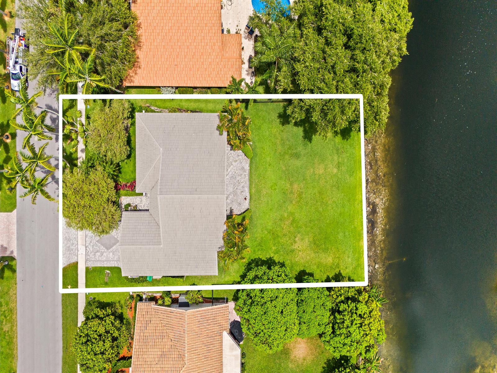 An aerial view shows a house with a gray roof and a large backyard waterfront — 1750 W Oak Knoll Circle, Davie FL 33324, DAVIE, FL