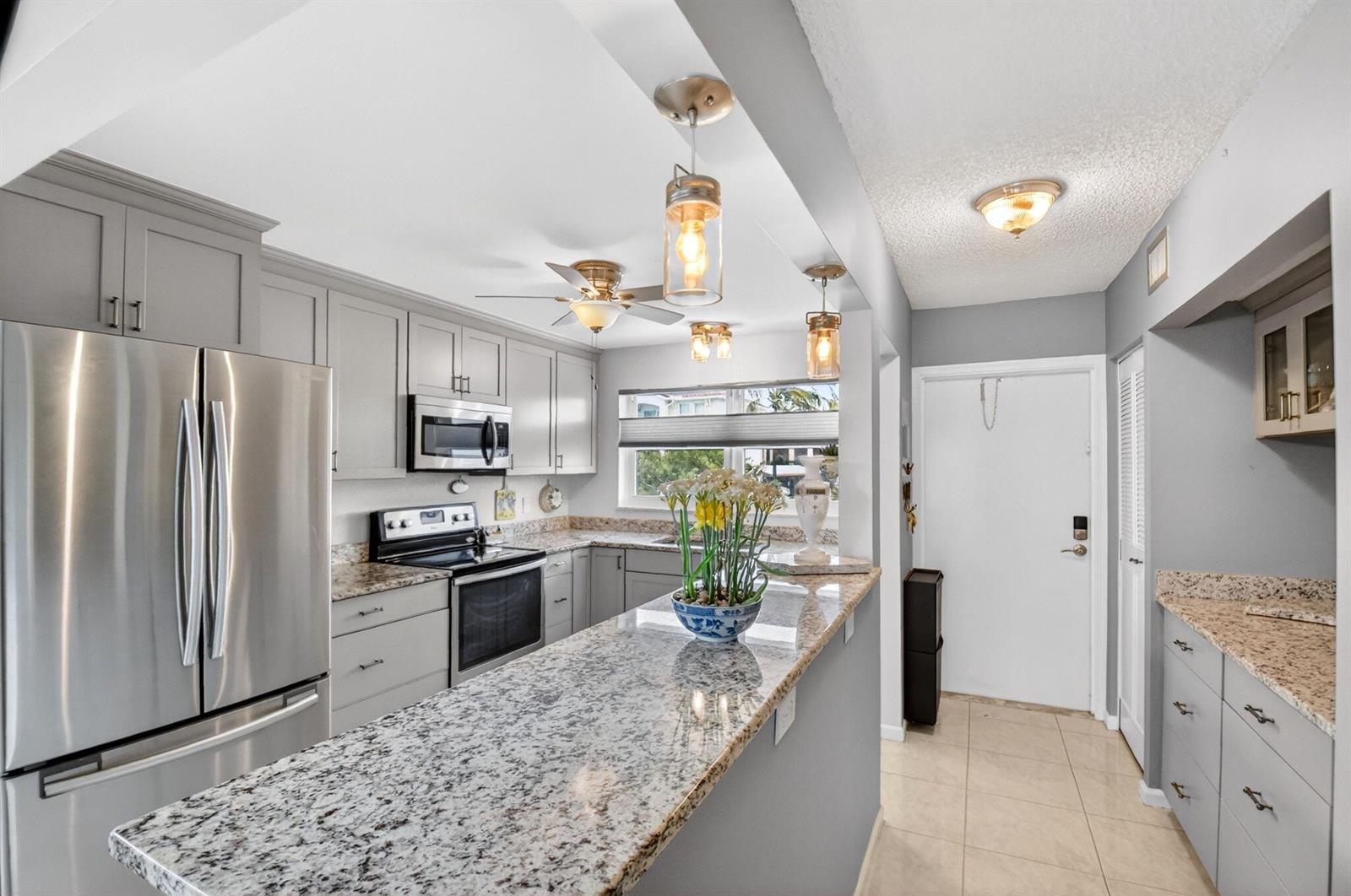 A kitchen features gray cabinets, granite countertops, stainless steel appliances, and a breakfast bar — 2016 S Federal Highway # E309, Boynton Beach FL 33435, BOYNTON BEACH, FL