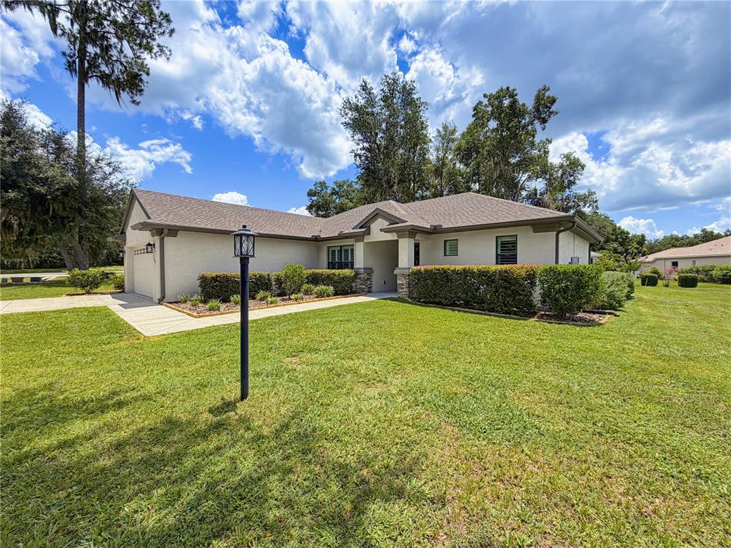 A single-story house with a beige stucco exterior, a shingled roof, and a front lawn — 2845 N APPLEDORE PATH, HERNANDO, FL