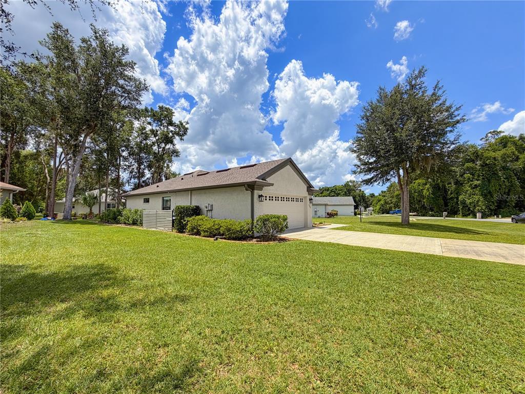 A side view of a single-story house with a garage, driveway, and large grassy yard — 2845 N APPLEDORE PATH, HERNANDO, FL