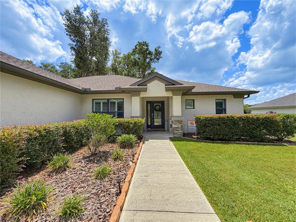 A concrete walkway leads to the front entrance of a single-story house with landscaping — 2845 N APPLEDORE PATH, HERNANDO, FL