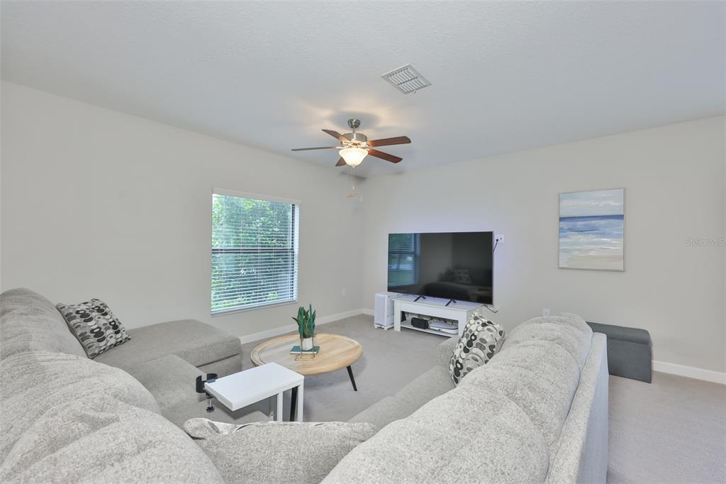 A living room features a large gray sectional sofa, a round wooden coffee table, and a television — 1922 CITRUS LAKE COURT, RUSKIN, FL