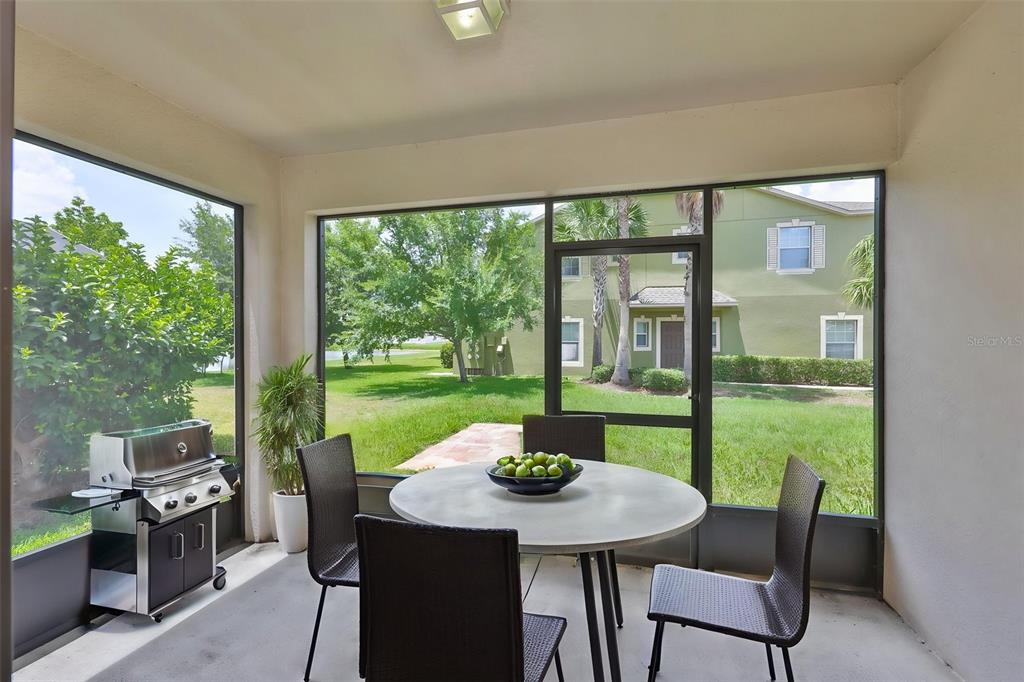 A screened-in patio features a round dining table, chairs, and a grill overlooking a lawn — 1922 CITRUS LAKE COURT, RUSKIN, FL