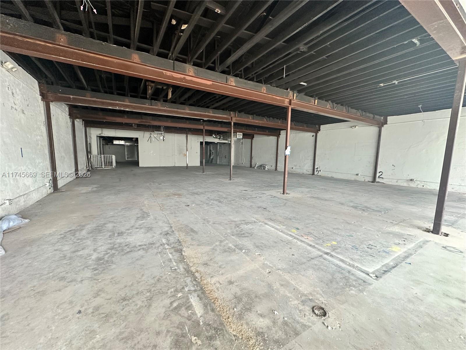 An empty, unfinished commercial warehouse space features exposed ceiling beams and concrete flooring — 2020 Harrison St, Hollywood FL 33020, HOLLYWOOD, FL