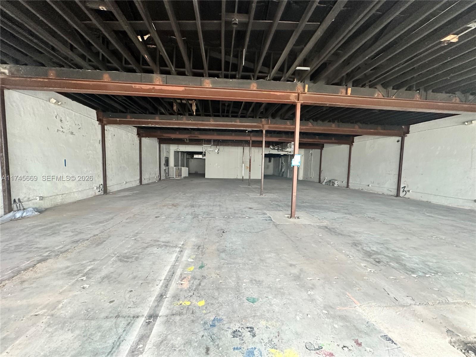 An empty, unfinished commercial space features exposed ceiling joists, concrete floors, and steel support beams — 2020 Harrison St, Hollywood FL 33020, HOLLYWOOD, FL