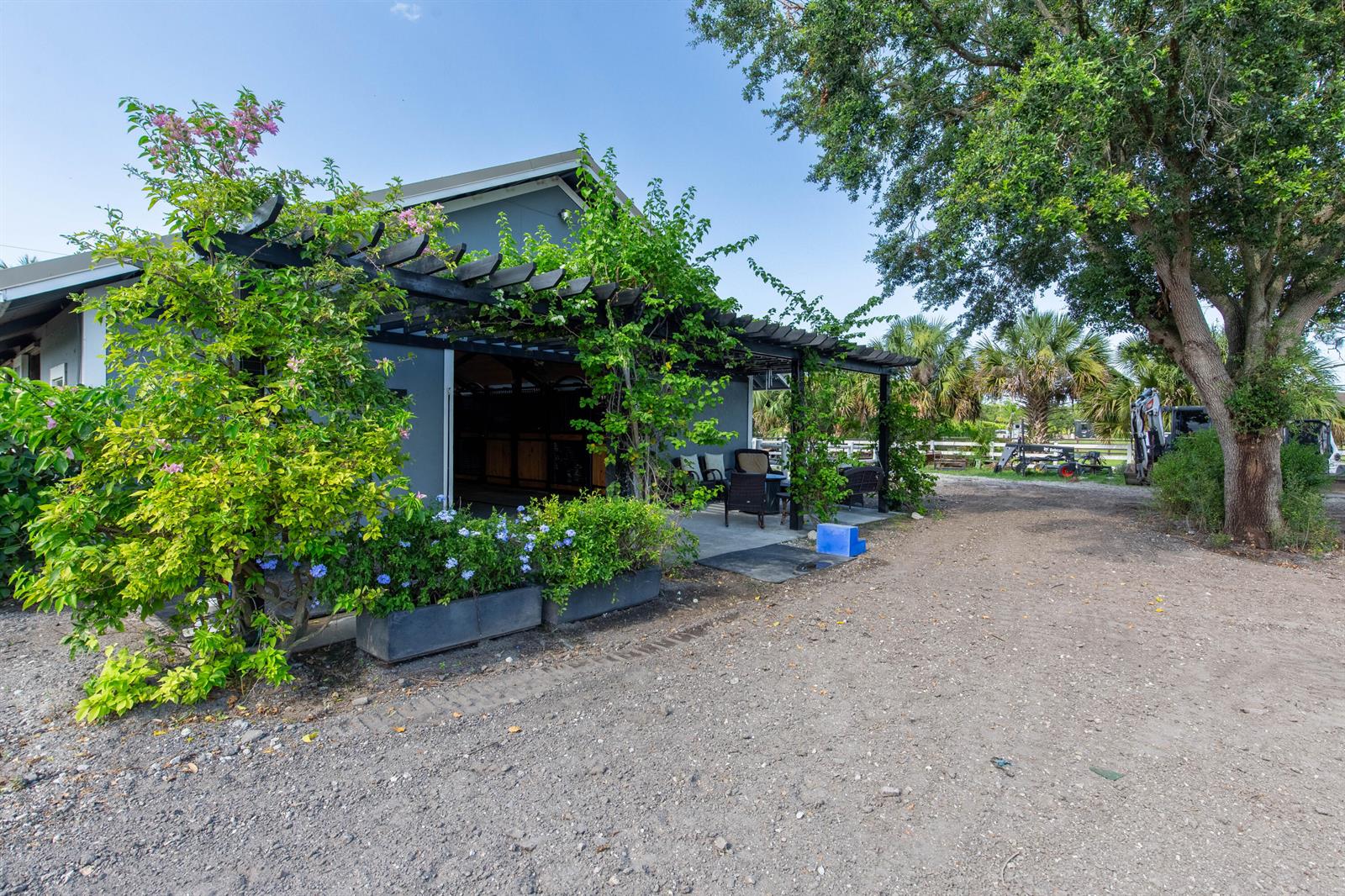 A gray building features a wooden pergola covered in climbing vines and outdoor patio furniture — 844 Arabian Drive, Loxahatchee FL 33470, LOXAHATCHEE, FL