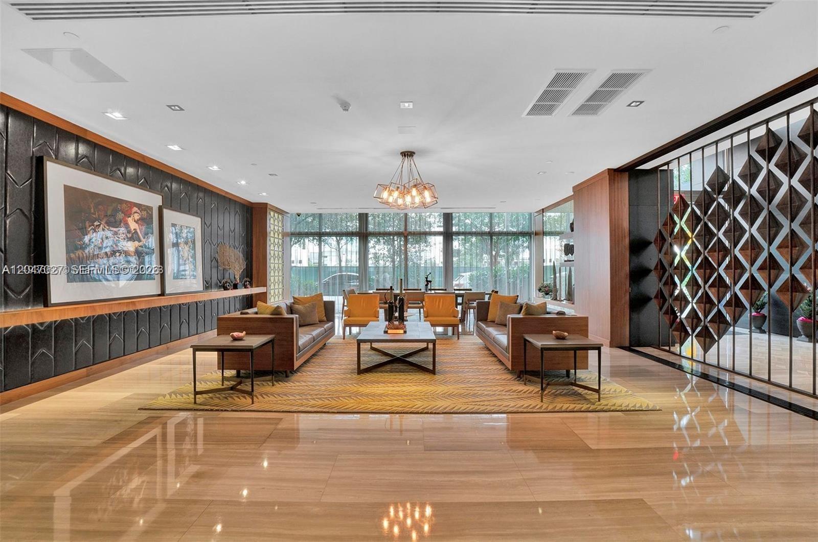 A modern lobby features a seating area with two sofas, a rug, and wood paneling — 3470 E Coast Ave # H0904, Miami FL 33137, MIAMI, FL