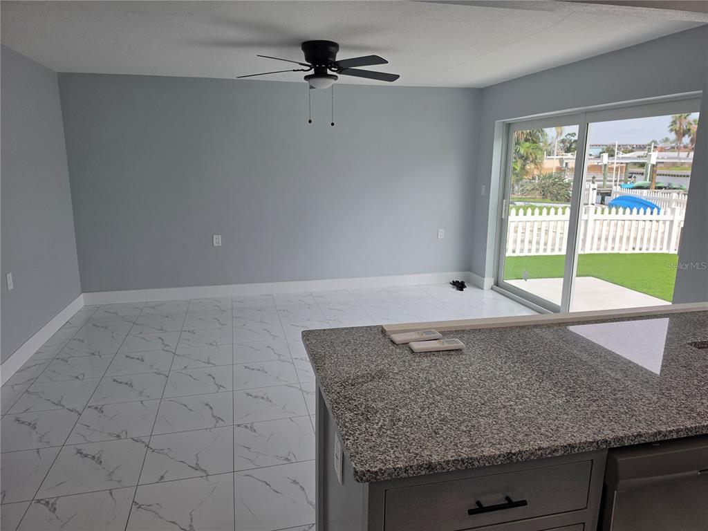 A room with white marble-look tile floors, a ceiling fan, and sliding glass doors — 145 131 AVENUE E UNIT 2, MADEIRA BEACH, FL