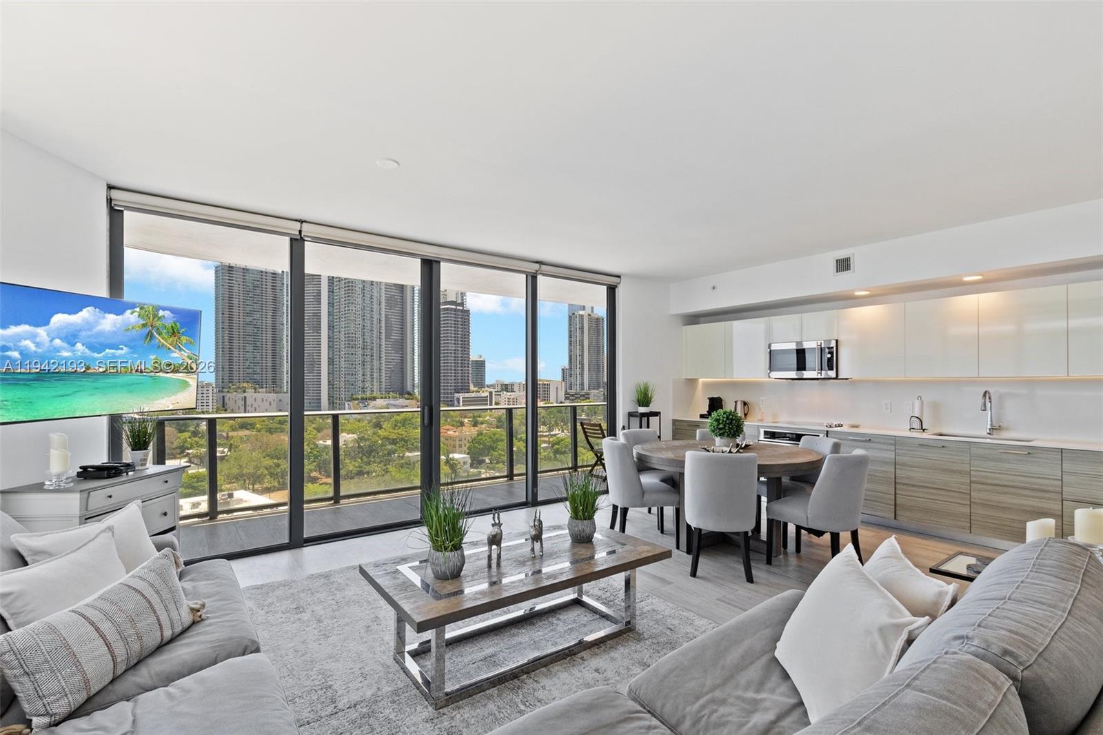 A modern living and dining area with floor-to-ceiling windows overlooking a city skyline — 121 NE 34th St # 1008, Miami FL 33137, MIAMI, FL