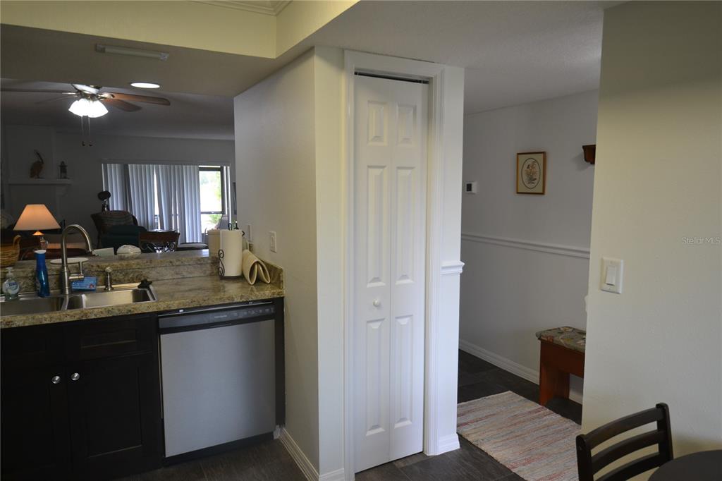 A kitchen with dark cabinets and a stainless steel dishwasher next to a closet door — 161 LAKESIDE DRIVE, OLDSMAR, FL