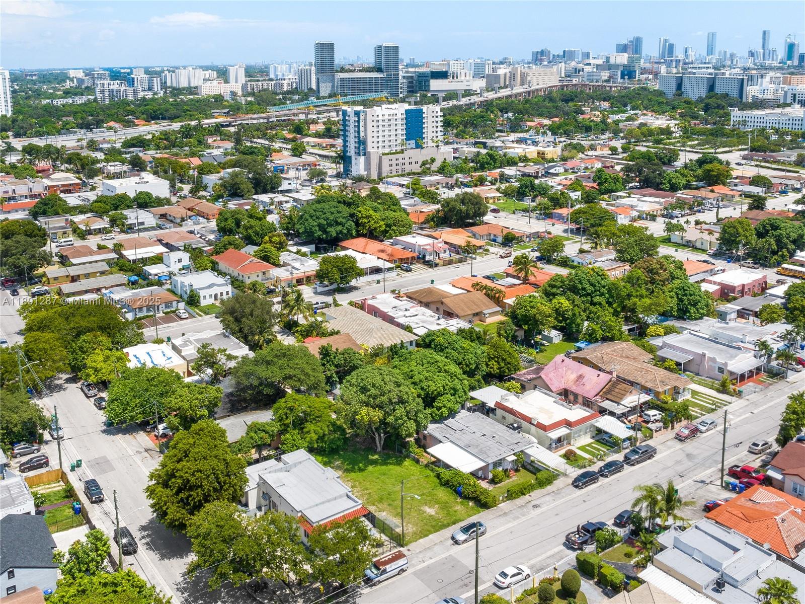 An aerial view shows a residential neighborhood with houses, trees, and distant city skyscrapers — 1881 NW 4th St, Miami FL 33125, MIAMI, FL