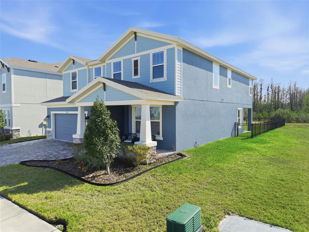 A two-story blue house with a front porch, a garage, and a fenced side yard — 17674 EVERLONG DRIVE, LAND O LAKES, FL