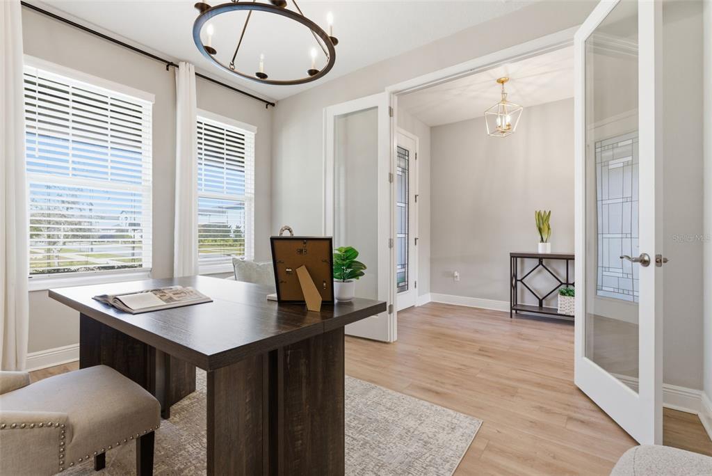 A home office features a dark wood desk, light wood flooring, and glass-paneled double doors — 17674 EVERLONG DRIVE, LAND O LAKES, FL