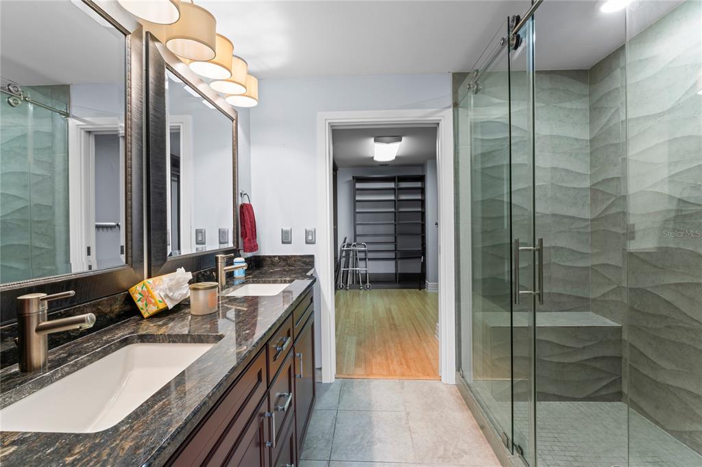 A bathroom features a double vanity with dark cabinets, granite countertops, and a glass-enclosed shower — 1108 N FRANKLIN STREET UNIT 707, TAMPA, FL