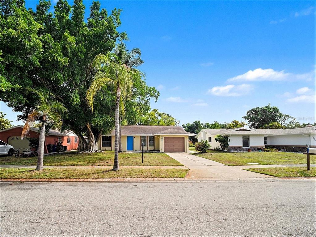 A single-story house with a blue front door, a garage, and large trees in front — 4037 MAVERICK AVENUE, SARASOTA, FL