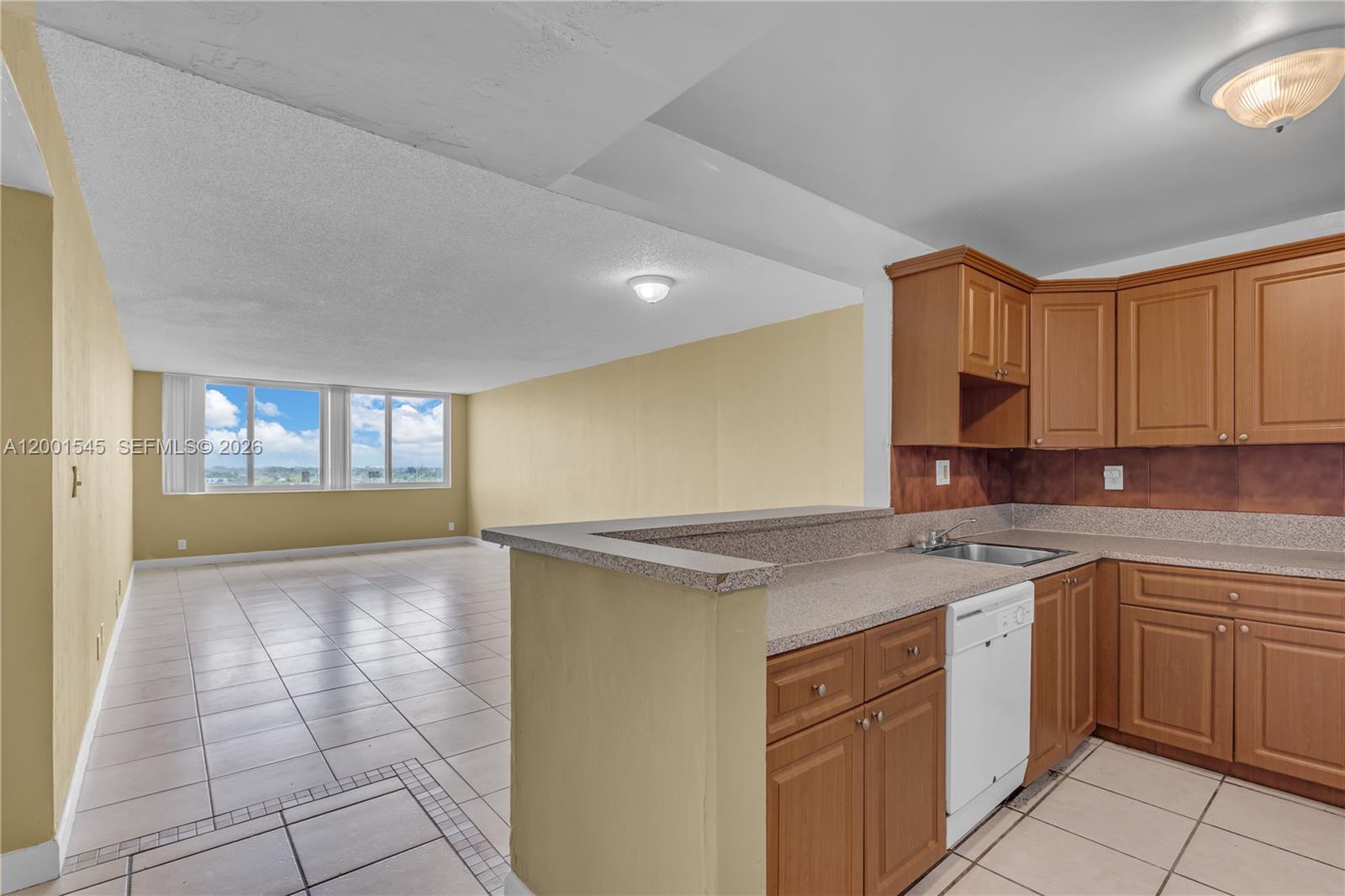A kitchen with wood cabinets and a breakfast bar overlooks an open living area — 9143 SW 77th Ave # B802, Miami FL 33156, MIAMI, FL