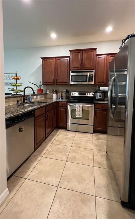 A kitchen features dark wood cabinets, stainless steel appliances, granite countertops, and light tile flooring — 772 SPRING FLOWERS TRAIL, BRANDON, FL