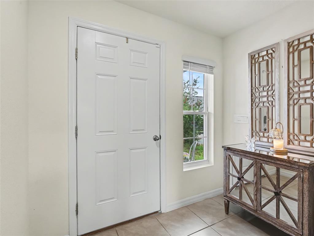 An entryway features a white door, a window, and a mirrored console table with wall art — 16525 MOSAIC OAR DRIVE, WIMAUMA, FL