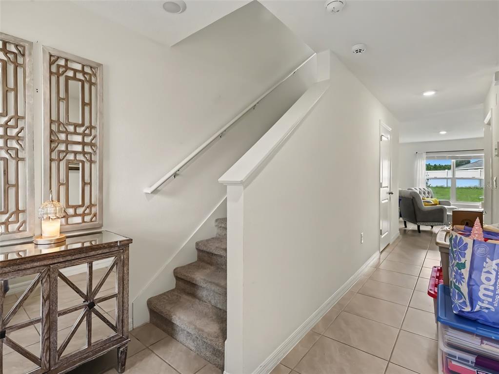 A carpeted staircase with a white railing sits beside a mirrored console table and hallway — 16525 MOSAIC OAR DRIVE, WIMAUMA, FL