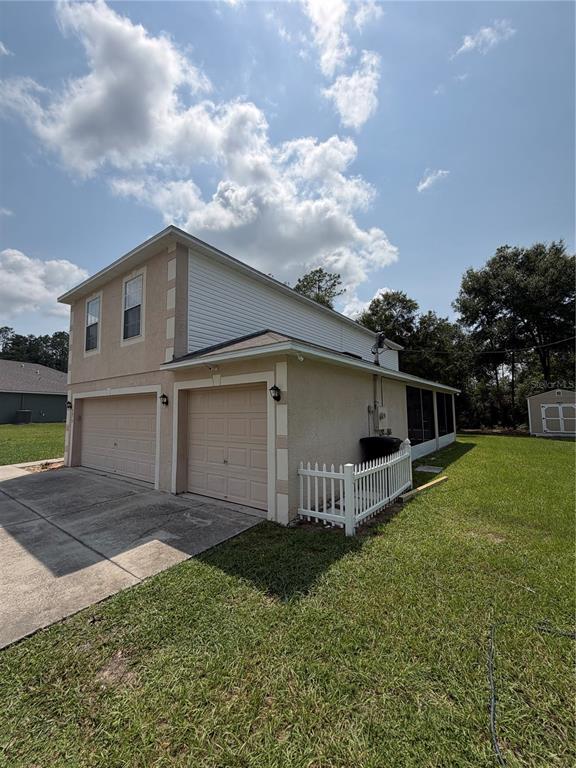 A two-story tan house with a three-car garage and a detached shed in the yard — 10078 N CARVER WAY, CITRUS SPRINGS, FL