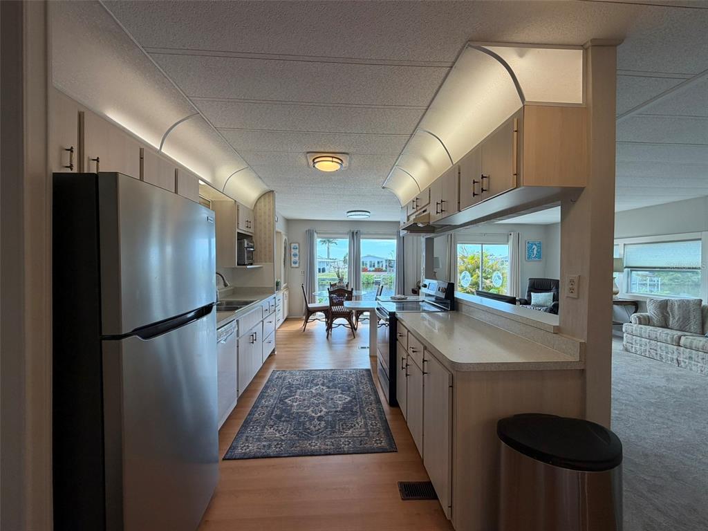 A galley-style kitchen features light wood cabinets, stainless steel appliances, and a view of water — 542 TAMPICO DRIVE, NORTH PORT, FL