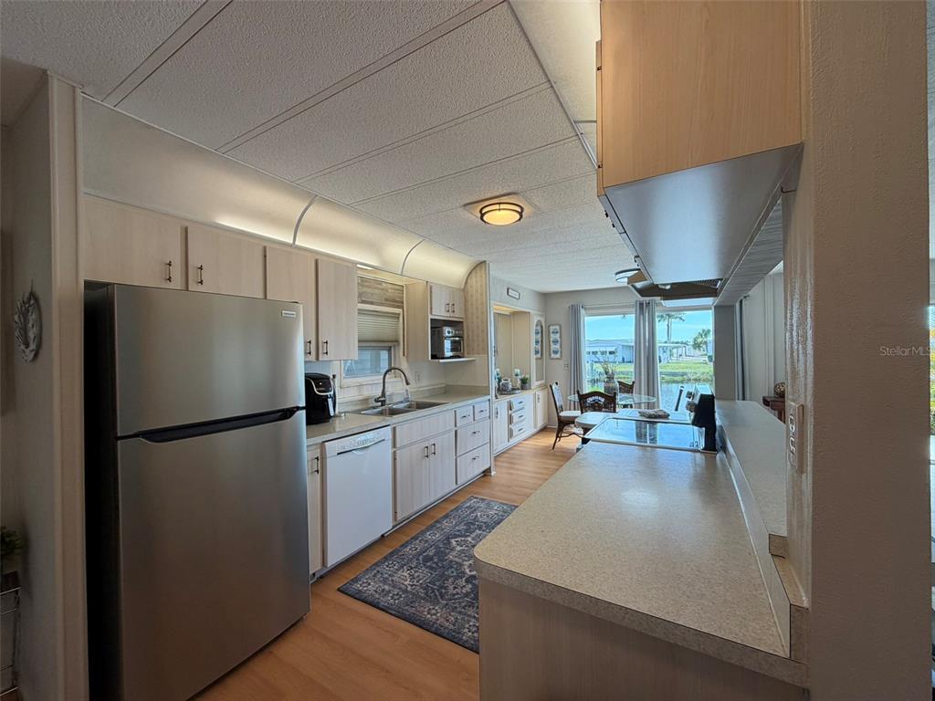 A kitchen with light wood cabinets, stainless steel appliances, and a view of the water — 542 TAMPICO DRIVE, NORTH PORT, FL