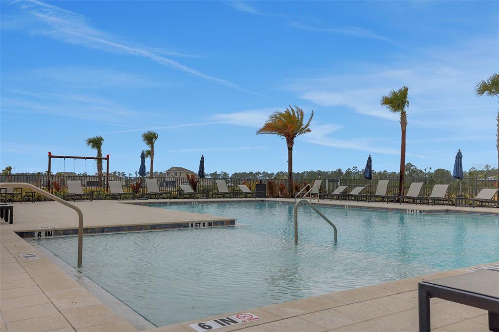 A swimming pool with a shallow entry area, lounge chairs, and palm trees outdoors — 17030 COTTONTAIL CIRCLE, PUNTA GORDA, FL