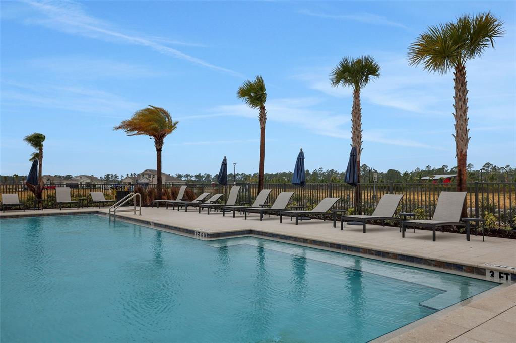 A swimming pool with lounge chairs and palm trees sits in a fenced outdoor area — 17030 COTTONTAIL CIRCLE, PUNTA GORDA, FL