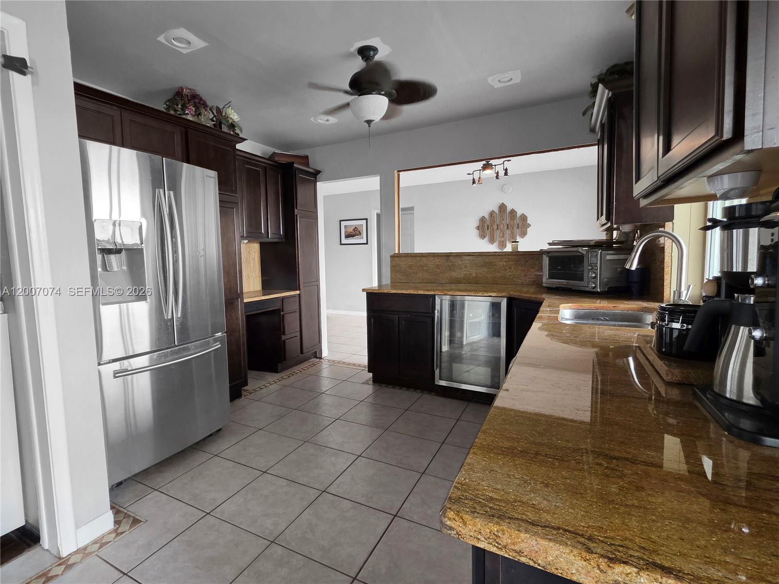 A kitchen features dark wood cabinets, granite countertops, stainless steel appliances, and tile flooring — 11661 NW 31st Pl, Sunrise FL 33323, SUNRISE, FL