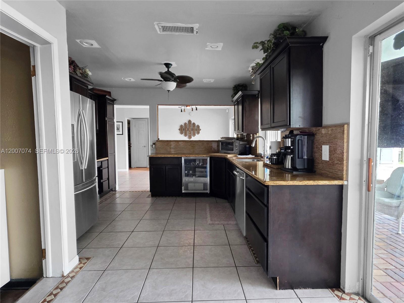 A kitchen features dark wood cabinets, granite countertops, stainless steel appliances, and light tile flooring — 11661 NW 31st Pl, Sunrise FL 33323, SUNRISE, FL