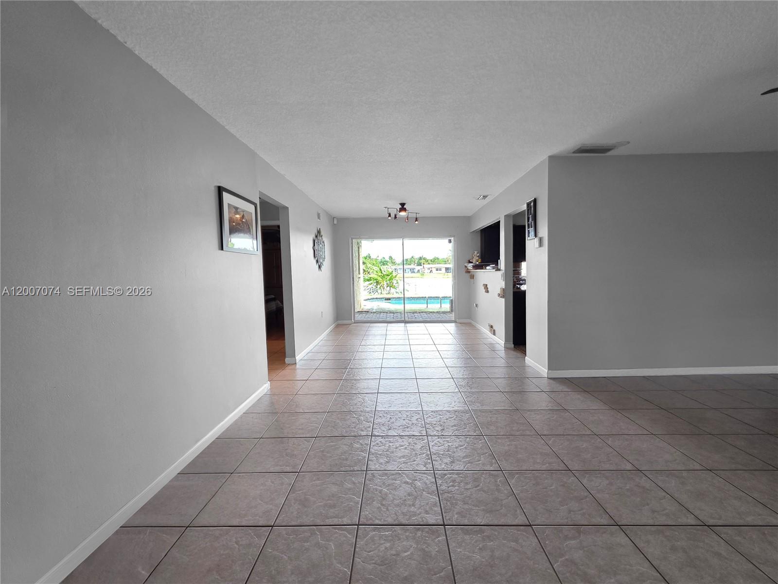 A spacious room with light gray walls, tile flooring, and sliding glass doors to a pool — 11661 NW 31st Pl, Sunrise FL 33323, SUNRISE, FL