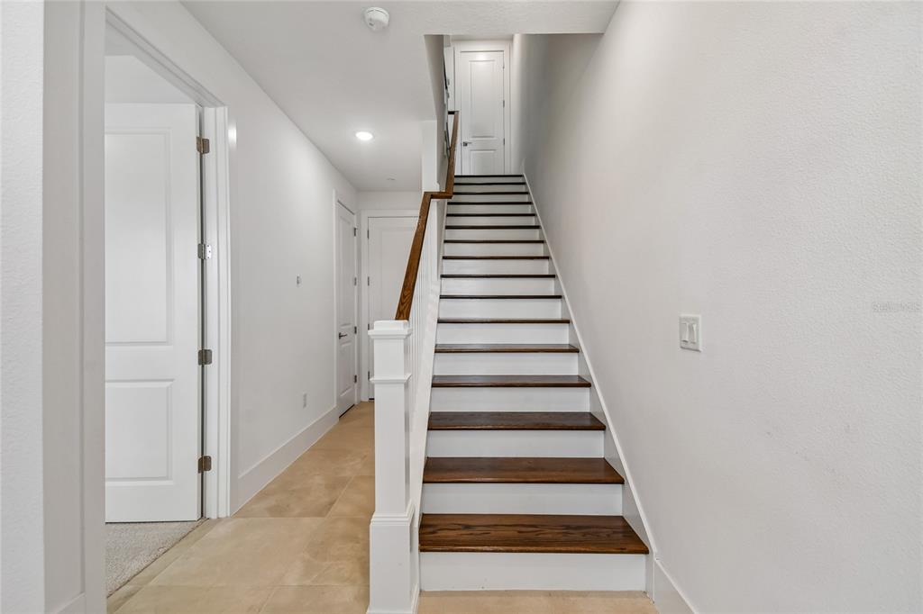 A staircase with dark wood treads and white risers leads to an upper landing — 234 PASQUALA WAY, OVIEDO, FL