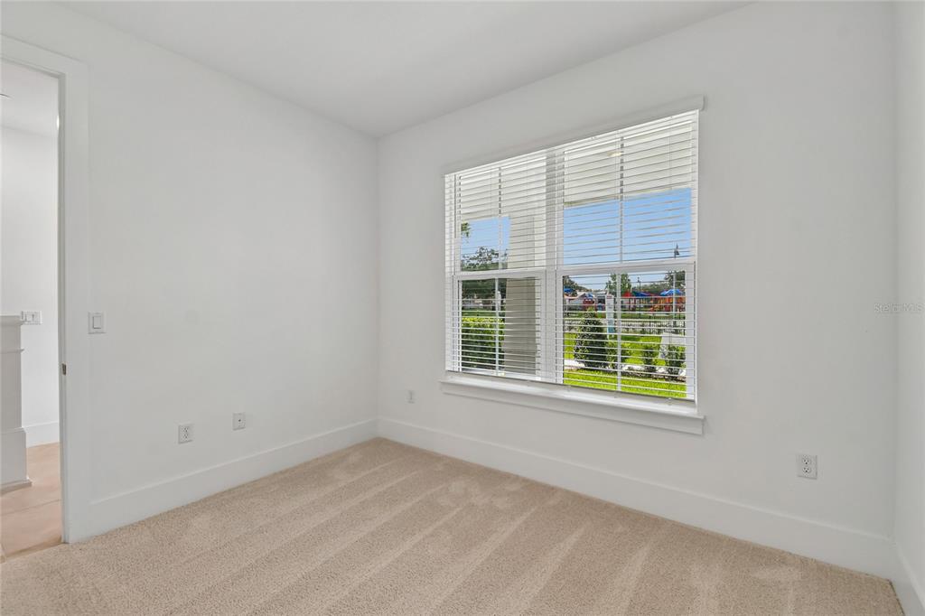 An empty bedroom with white walls, beige carpet, and a window overlooking a playground — 234 PASQUALA WAY, OVIEDO, FL