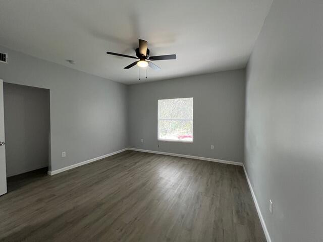 An empty bedroom features gray walls, wood-look flooring, a ceiling fan, and a window — 520 N E Street, FL 33460, FL