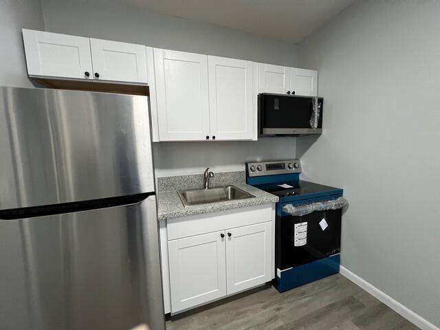 A kitchen features white cabinets, stainless steel appliances, a sink, and gray flooring — 520 N E Street, FL 33460, FL