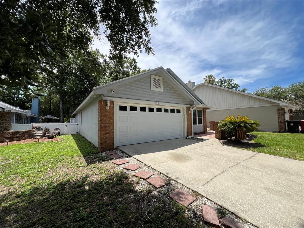 A single-story house exterior features a white garage door, brick accents, and a concrete driveway — 3159 BERRIDGE LANE, ORLANDO, FL