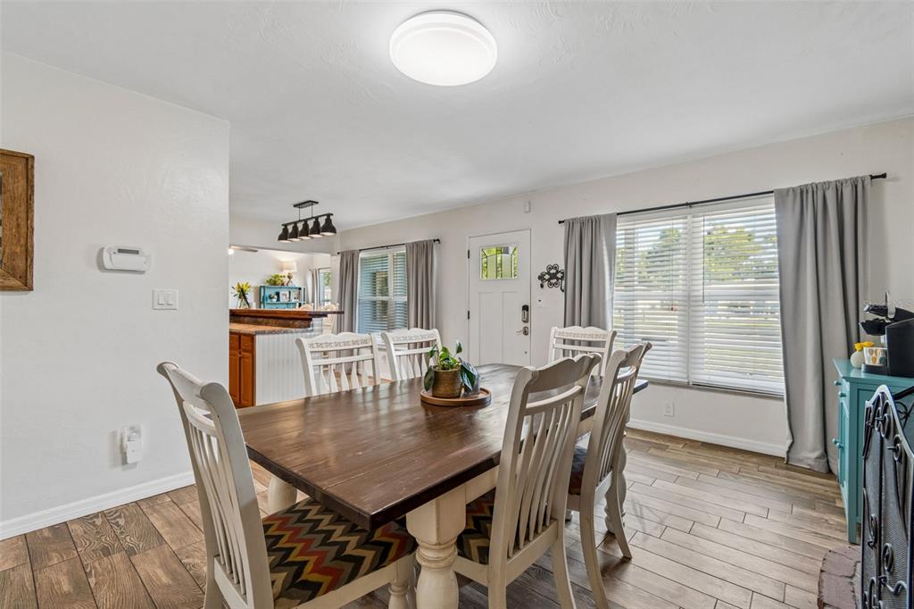 A dining room with a wooden table, white chairs, and a hutch near a kitchen — 10748 VILLAGE GREEN AVE, SEMINOLE, FL