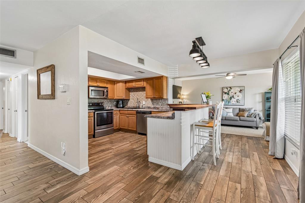 A kitchen with a wood-topped breakfast bar overlooks a dining area with a brick fireplace — 10748 VILLAGE GREEN AVE, SEMINOLE, FL