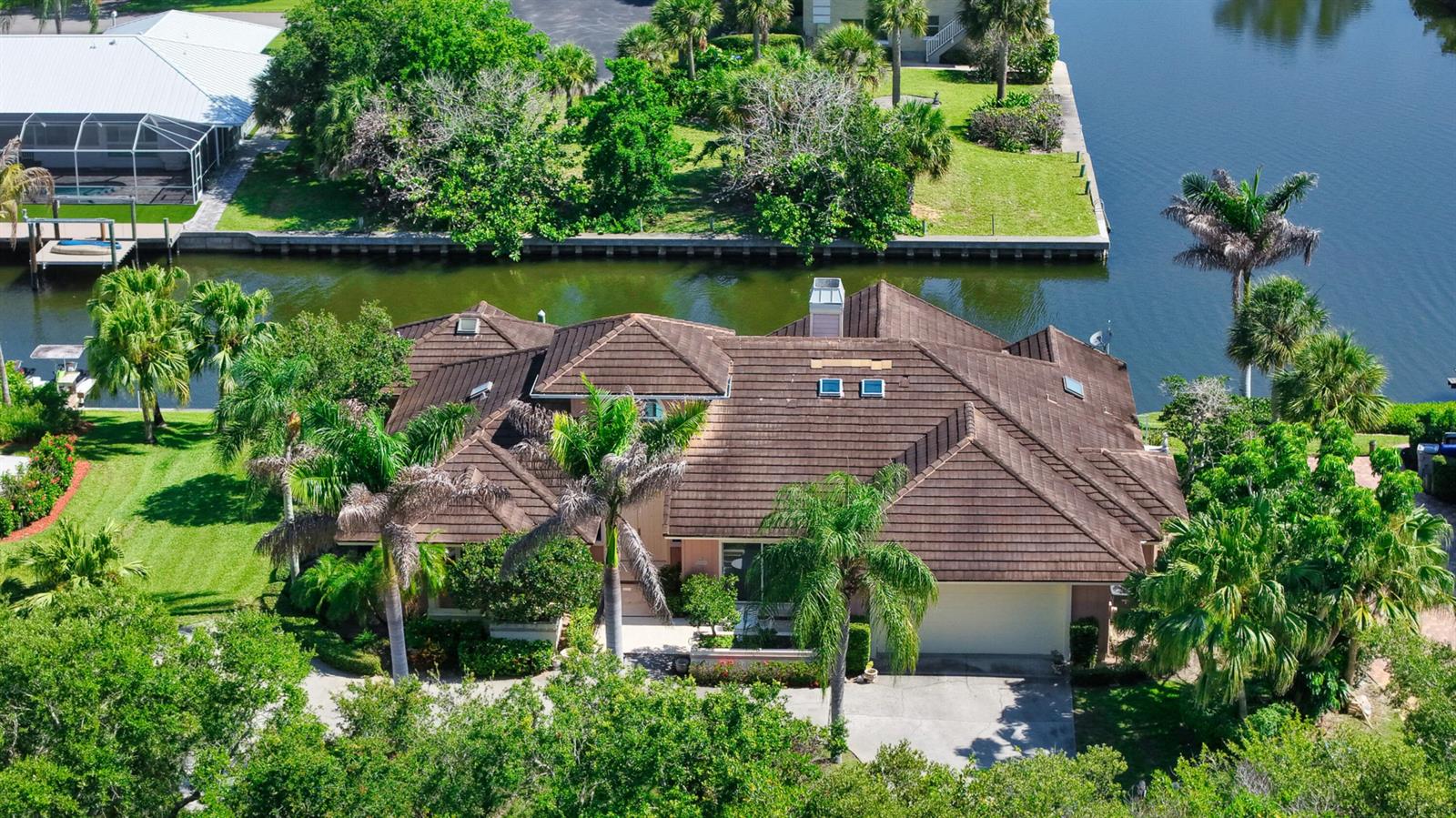An aerial view of a single-story house with a brown tile roof near a canal — 3500 Marsha Lane, Vero Beach FL 32967, VERO BEACH, FL