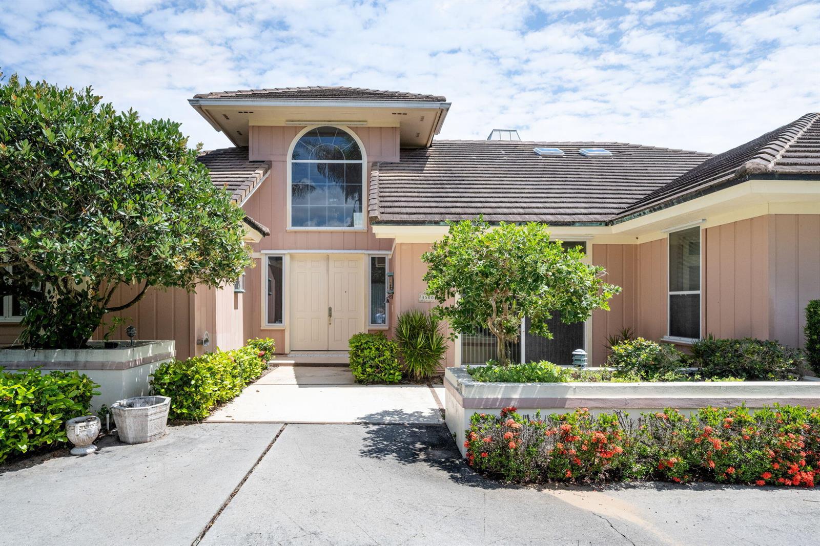A two-story house with a beige exterior, arched window, and a concrete driveway — 3500 Marsha Lane, Vero Beach FL 32967, VERO BEACH, FL