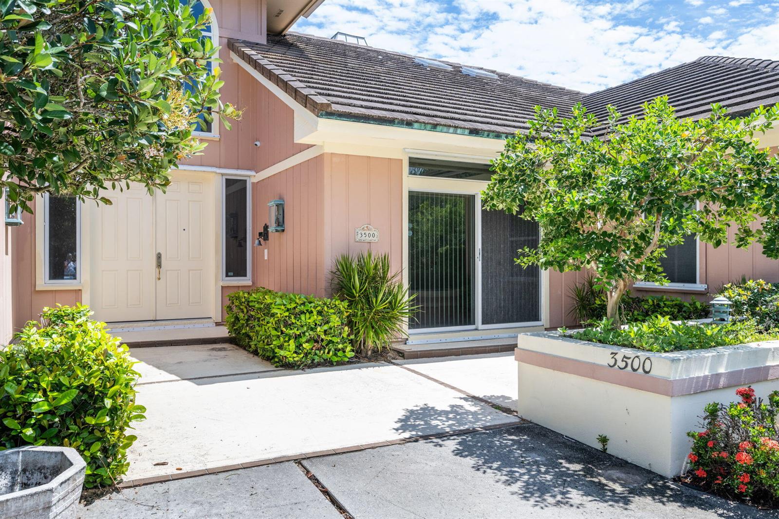 The exterior of a pink house features a double front door and a sliding glass door — 3500 Marsha Lane, Vero Beach FL 32967, VERO BEACH, FL