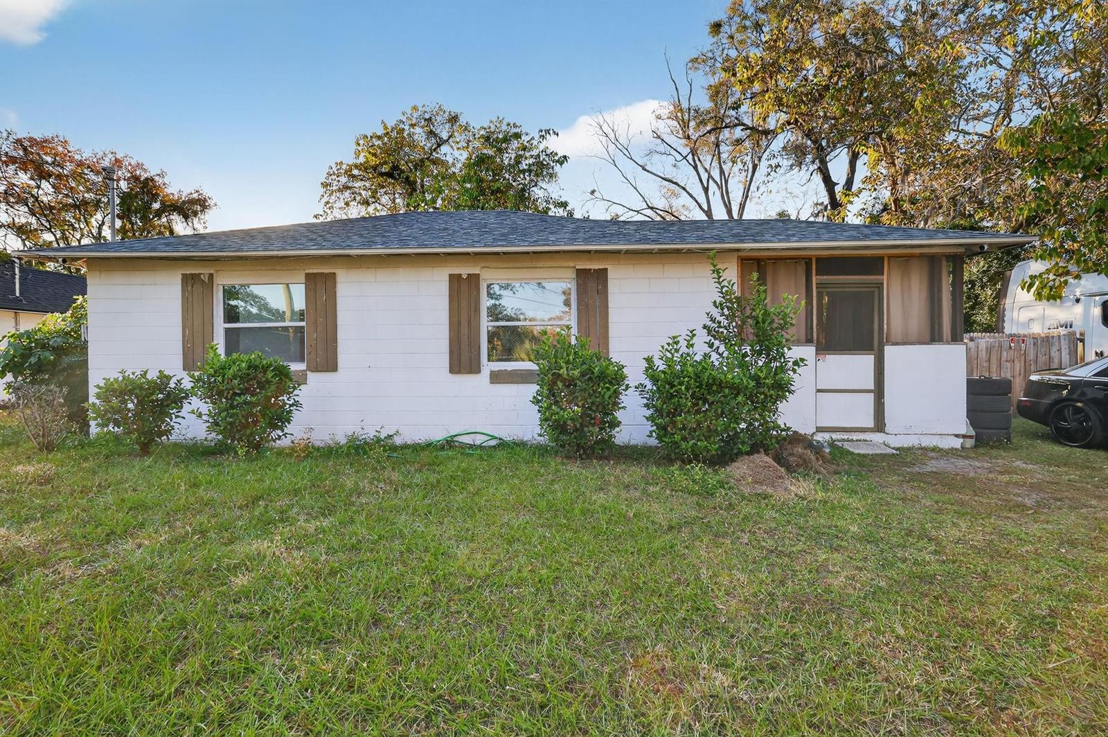 A single-story white concrete block house with a screened porch and brown window shutters — 1030 NW 13 Avenue, FL 34475, FL