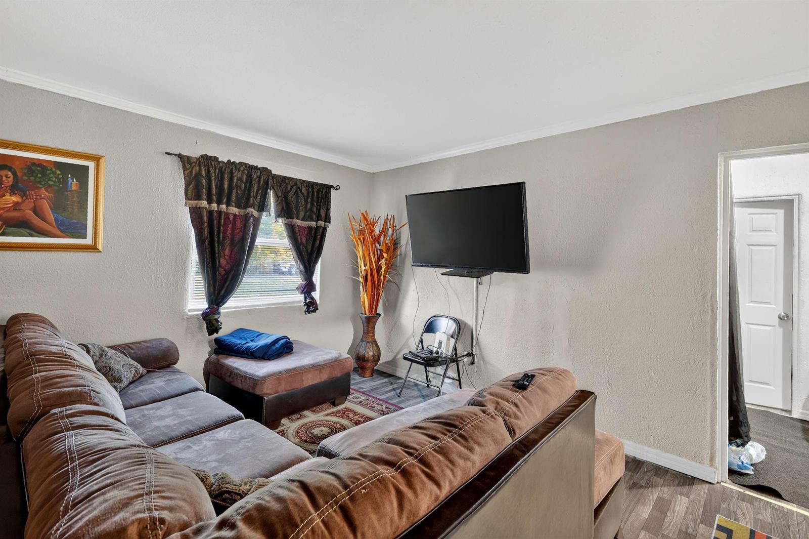 A living room features a brown sectional sofa, a wall-mounted television, and a window — 1030 NW 13 Avenue, FL 34475, FL